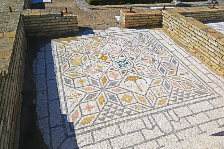 Mosaico romano geométrico de colores en el yacimiento de Itálica, de donde proceden muchos de los mosaicos del Palacio de Lebrija