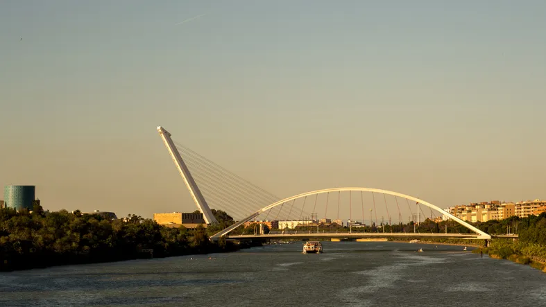 Puente del Alamillo de Calatrava sobre el Guadalquivir al atardecer, junto al parque, con el arco del Puente de la Barqueta al fondo