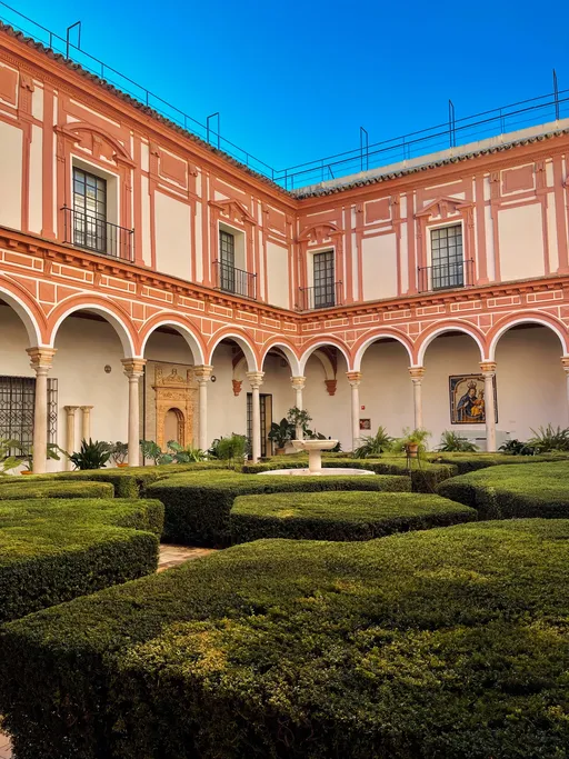 Claustro del Museo de Bellas Artes de Sevilla, antiguo convento de la Merced, con arcos, fachadas en rojo almagra y jardín de setos