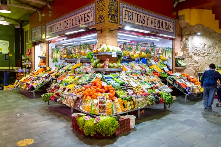 Puesto de frutas y verduras con rótulo de azulejos dentro del Mercado de Triana, en Sevilla