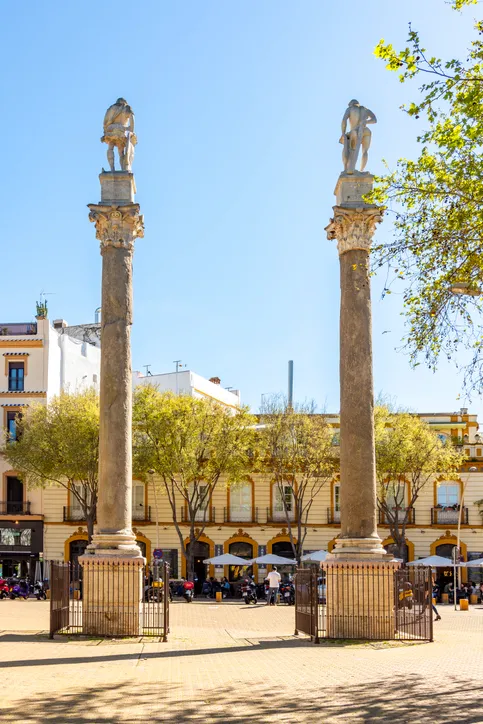 Detalle de las columnas de la Alameda de Hércules con sus capiteles corintios y las estatuas, y fachadas de colores al fondo